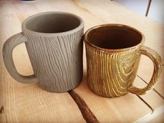 two coffee mugs sitting next to each other on top of a wooden table,