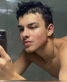 a shirtless man taking a selfie in front of a bathroom mirror with his cell phone