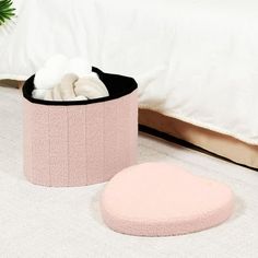 a pink and black container sitting on top of a bed next to a white pillow