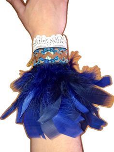 a woman's hand wearing a blue feather wrist corsage