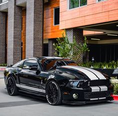 a black and white mustang parked in front of a building