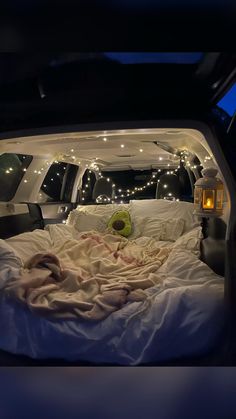 the bed in the back of a van is covered with blankets and lights