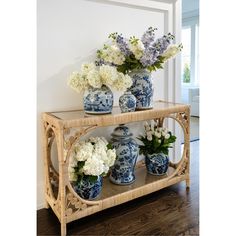 blue and white vases are sitting on a shelf with flowers in them, along with other floral arrangements