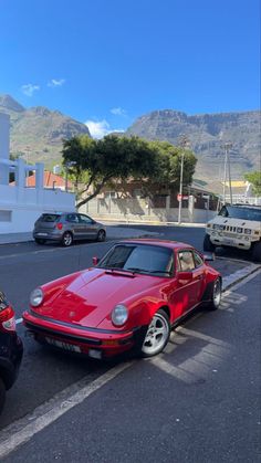 two cars are parked on the side of the road in front of a mountain range