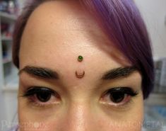 a woman with purple hair has a nose piercing on her left side and green eyeshade