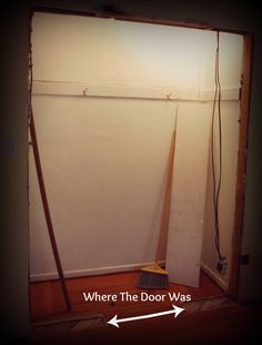 a broom is sitting on the floor in front of a white wall with an arrow pointing to where the door was