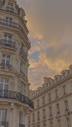 an ornate building with balconies and balconyes against a cloudy sky at sunset