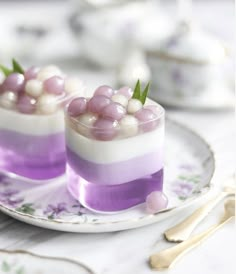 two small desserts with purple and white frosting on them sitting on a plate