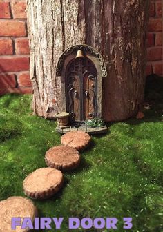 a fairy door in the middle of some green grass next to a wooden tree stump