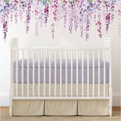 a white crib with purple flowers hanging from the ceiling