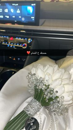 a bouquet of flowers sitting on top of a white cloth covered car dash board with the radio in the background