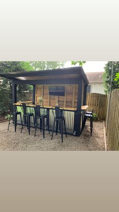 an outdoor bar with chairs and tables in the back yard, next to a fence