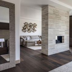 a living room with wood flooring and a large stone fireplace in the middle of it