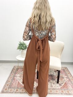 Get ready to lounge in style with the Layla Drawstring Jumpsuit. This mocha brown ribbed knit jumpsuit features a loose fit and adjustable shoulder strap for ultimate comfort. The wide leg design and hidden side seam pockets make it both trendy and functional. Perfect for a day of relaxation or running errands in style. Pairs well with our floral mesh tops! True to size Model is 5'4 and wearing a small 60% Polyester, 35% Rayon, 5% Spandex Pant Romper With Sweater, Cheap Jumpsuits And Rompers For Day Out In Fall, Dolman Sweater Over Jumpsuit, Cheap Women's Fall Jumpsuits And Rompers, Cheap Fall Jumpsuits And Rompers For Day Out, Fall Jumpsuits & Rompers, Fashion Staples For Women, Boho Hippy Outfits, Modern Bohemian Outfits