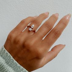 a woman's hand wearing a ring with two small diamonds on the middle of it