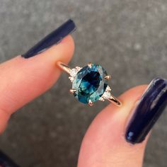 a woman's hand holding a ring with an oval blue stone in the middle