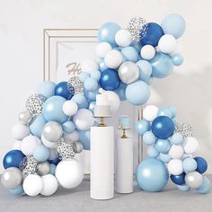 blue and white balloons are arranged in the shape of an arch, with a sprayer next to it