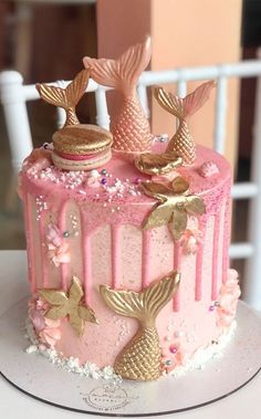 a pink cake with gold mermaid decorations on top