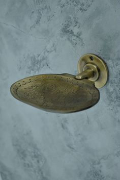 an antique brass toilet paper holder on the wall