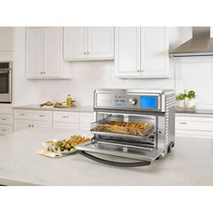 an open oven with food in it sitting on a kitchen counter next to white cabinets