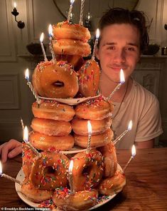 a man sitting in front of a large stack of donuts on top of a table