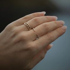 a woman's hand with two gold rings on top of her finger and one in the middle