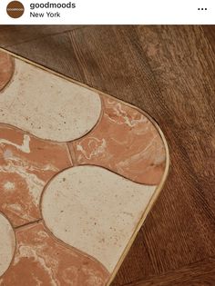 a close up of a rug on a wooden floor with brown and white tiles in the middle