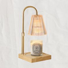 a candle on a wooden shelf next to a lamp