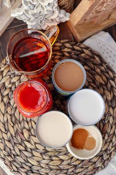 four different types of sauces in small bowls on a woven basket with napkins