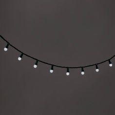 a string of white light bulbs on a black wire against a gray background with copy space