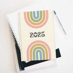 a spiral notebook with the number 2055 printed on it next to a notepad and pen