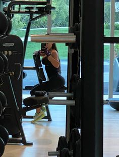 a woman taking a photo in the gym with her cell phone while sitting on an exercise machine