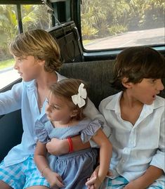 three children sitting in the back seat of a car with their hands on their hips