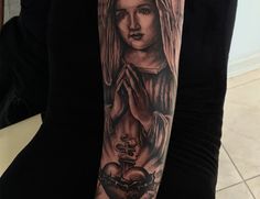 Madonna Blessing Heats Black & Gray Photo Realism Portrait Tattoo By Rene Cristobal, A Guest Artist At Iron Palm Tattoos. The Madonna is a representation of Mary praying. The word "Madonna" comes from the Italian "ma donna," which means "my lady". Although usually depicted with baby Jesus it is also popular to see Mary praying or blessing something. We're open late night until 2AM. Call 404-973-7828 or stop by for a free consultation. Walk Ins are welcome. Mary Praying, Gray Photo