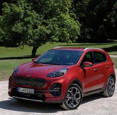 a red car parked in front of some trees