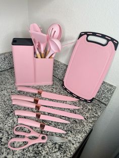 pink utensils are sitting on a counter next to a pink box with utensils in it