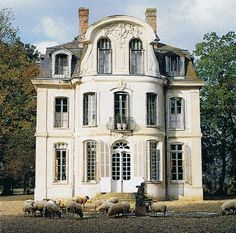 a large white house with many windows and sheep grazing in front of the door area