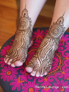 the feet are decorated with henna designs on top of a stool and pink flowers