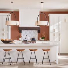 a kitchen with an island and stools in the center, surrounded by white cabinets