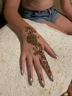 a woman's hand with henna on it sitting on top of a table