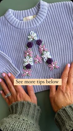 two hands holding onto a sweater with crochet flowers on it and the words see more tips below