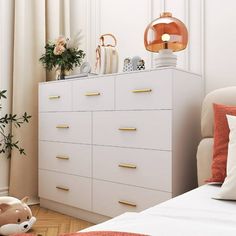 a white dresser with gold handles in a bedroom