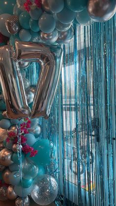 balloons and streamers are hanging from the ceiling in front of a blue backdrop with silver foil