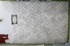 a kitchen wall that is being remodeled with white tile and green grouting on the walls