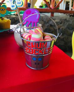 a bucket filled with candy sitting on top of a red table