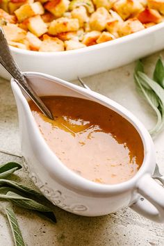 a gravy in a white gravy dish next to a casserole dish