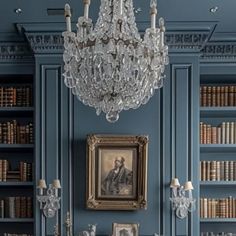 a room with bookshelves, chandelier and pictures on the wall in it