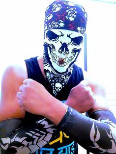 a man wearing a skull mask and bandana with his hands crossed in front of him