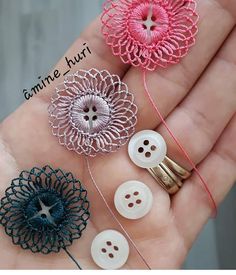 four different types of buttons in the palm of someone's hand with yarn and thread