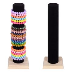 a stack of multicolored beads sitting on top of a wooden stand next to a black pole